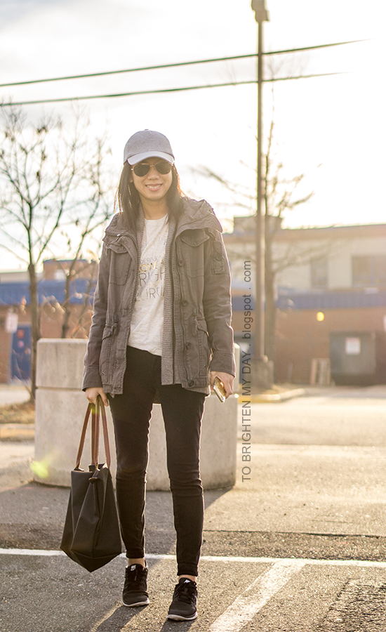 light gray baseball cap, gray military jacket, taupe open cardigan, winter graphic tee, black skinny jeans, black sneakers