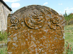 angel in a roundel writing on a tablet with a quill, flanked by cherubs